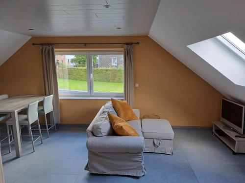 sala de estar con sofá, mesa y ventana en L'Etable d'Evelyne en Bastogne