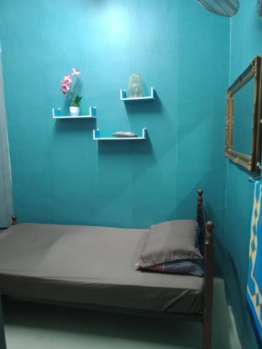 a blue room with a bed with two shelves at Mom's home in Pasir Gudang