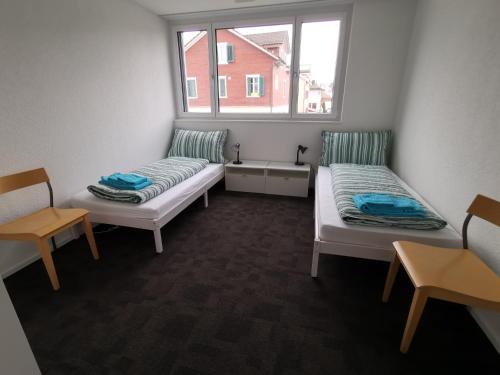 two beds in a room with a window at Ferienwohnung Hirschen in Gossau