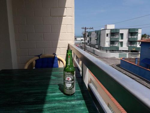 una bottiglia di birra seduta su un tavolo sul balcone di Apartamento 1 quarto Mongaguá a Mongaguá
