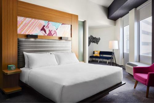 a bedroom with a large white bed and a chair at Aloft Leawood-Overland Park in Overland Park