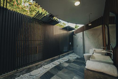 a bathroom with a toilet and a black fence at La Cima Eco Hotel in Buenavista
