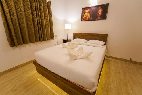 Schlafzimmer mit einem Bett mit weißer Bettwäsche und Kissen in der Unterkunft La Tamara Luxury in Puducherry