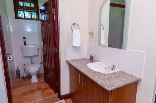 y baño con lavabo, aseo y espejo. en Villa (2) Del Sol: Lakefront and Cruise Boat en Kisumu
