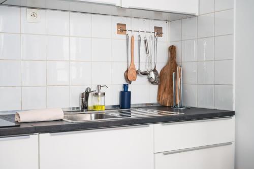 - une cuisine carrelée de blanc avec évier et ustensiles dans l'établissement LE Dina Robin, Studio 5mn plage à pied, wi-fi, parking privé à 5 min, à La Grande Motte