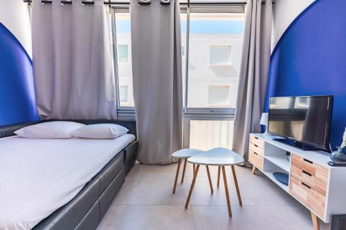une chambre avec un lit, une télévision et une chaise dans l'établissement LE Dina Robin, Studio 5mn plage à pied, wi-fi, parking privé à 5 min, à La Grande Motte