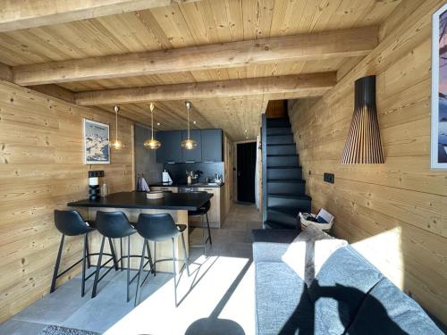 a kitchen with wooden walls and a bar with stools at Val Thorens - Cosy Duplex avec Vue Pied des pistes Silveralp 570 in Val Thorens