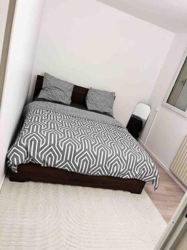 a bed with a black and white comforter in a bedroom at Logement entier chambre+salon + jardin & terrasse in Les Ulis