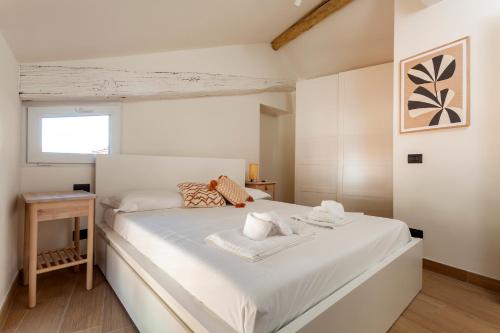 Un dormitorio con una gran cama blanca con toallas. en Una mansarda sul Lago di Como, en Como