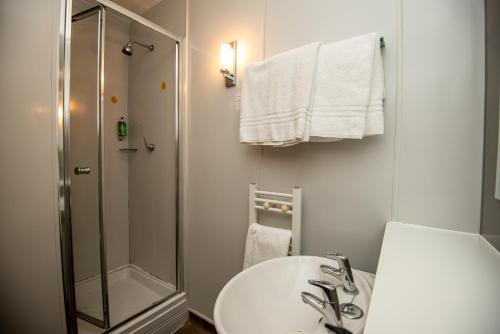 baño blanco con ducha y lavamanos en The George Inn en Selby