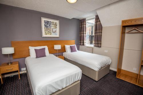 een hotelkamer met 2 bedden en een raam bij The George Inn in Selby