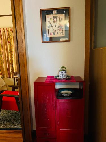 a red cabinet in a room with a picture on the wall at Eishinan 栄進庵 in Fuji