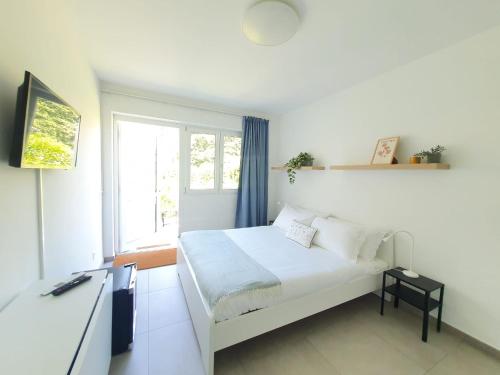 una camera bianca con un letto e una finestra di Le Betulle Studios by Quokka 360 - studio apartments by the Origlio lake a Origlio