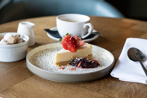 un morceau de gâteau sur une table avec une tasse de café dans l'établissement The Binsted Inn, à Alton