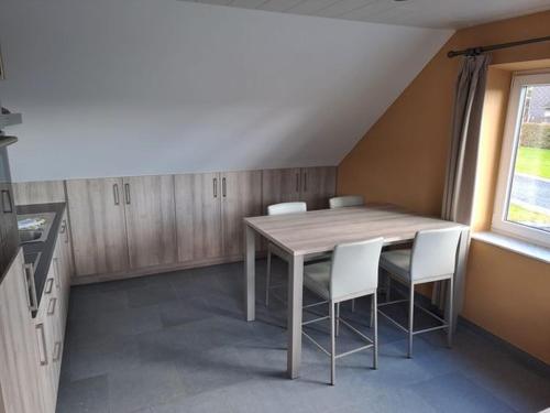 - une cuisine avec une table en bois et des chaises blanches dans l'établissement La Ferme Villa, à Bastogne