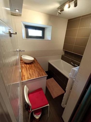 La salle de bains est pourvue d'un lavabo et d'un tabouret rouge. dans l'établissement Chez PLYZ - Maison familiale Since 2010, à Mesnois