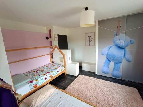 une chambre avec un ours en peluche bleu suspendu au mur dans l'établissement Chez PLYZ - Maison familiale Since 2010, à Mesnois