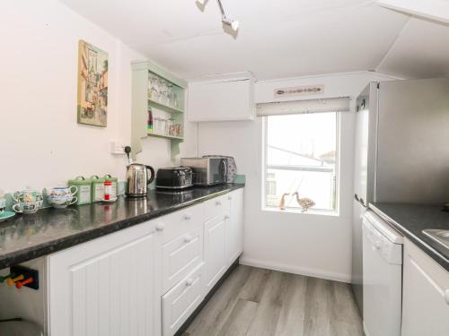 a kitchen with white cabinets and a counter top at Suzanne's Beach Hut in Norwich