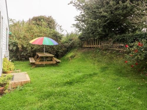 a picnic table with an umbrella in a yard at Suzanne's Beach Hut in Norwich