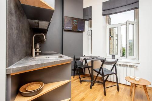 a kitchen with a sink and a table with chairs at Design apartments between National Art Museum and Arena Riga in Rīga