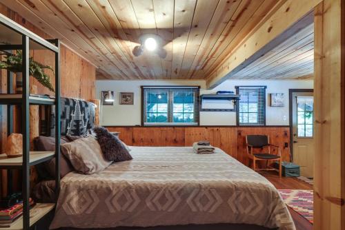 - une chambre avec un lit dans une pièce dotée de murs en bois dans l'établissement Dreamy Woodland Hideaway with Grills and Fire Pit!, à Camp Connell