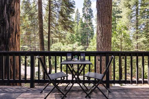 a black table and chairs on a deck with trees at Decks, Grills and Fire Pit Camp Connell Hideaway! in Camp Connell