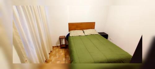 a small bedroom with a green bed and a curtain at Antarki Guest House in Cusco