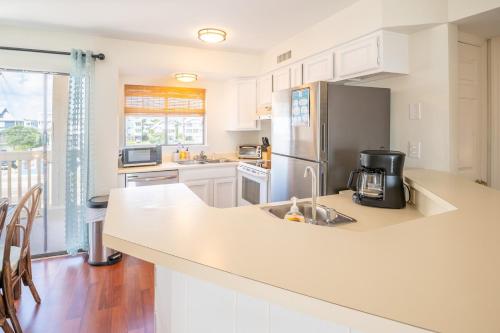 a kitchen with white cabinets and a stainless steel refrigerator at Oceanfront Condo with Pool - Salty Hammocks A6 in Carolina Beach