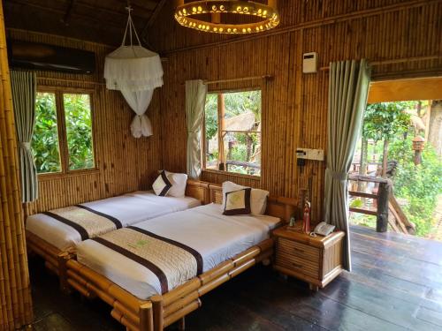 two beds in a room with wooden walls and windows at Bamboo Eco Village in Can Tho