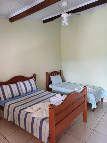 a bedroom with two beds and a ceiling fan at Casa do Éden in Paraty