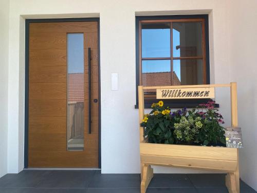 una puerta de madera y un banco con flores al lado en Biohof-Feichtinger, en Zell am Moos