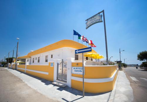 a yellow and white building with a sign on it at Albergo Europa in Marina di Mancaversa