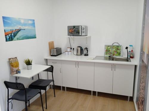 a kitchen with white cabinets and a table and chairs at Tropical Suite in Benalmádena