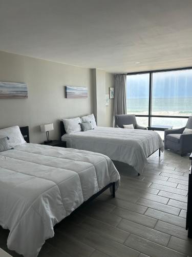 a hotel room with two beds and a couch at Oceanside Inn in Daytona Beach