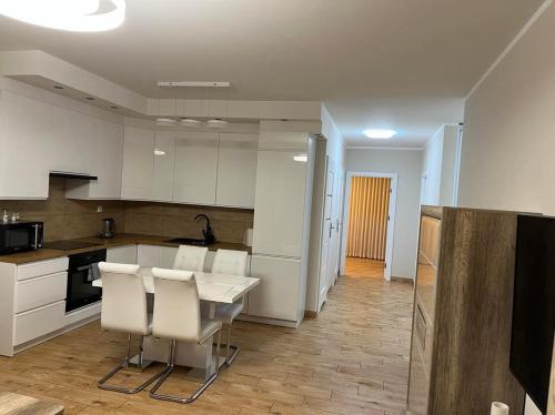 a kitchen with white cabinets and a table and chairs at Apartament Sielawy 21 parking free in Poznań
