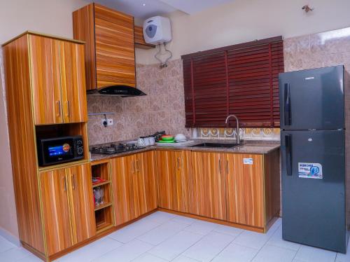E&T Luxury Apartments في أويو: مطبخ بدولاب خشبي وثلاجة