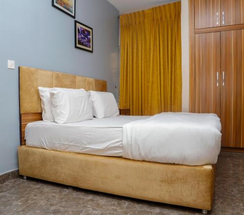 a bedroom with a large bed with white sheets at E&T Luxury Apartments in Uyo