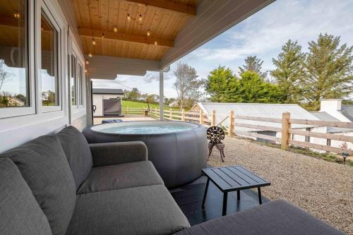 a living room with a couch and a hot tub at Luxury Log Cabin with Private Hot Tub & Sea Views in Letterkenny