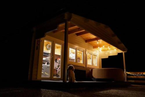 a woman standing in front of a refrigerator at night at Luxury Log Cabin with Private Hot Tub & Sea Views in Letterkenny
