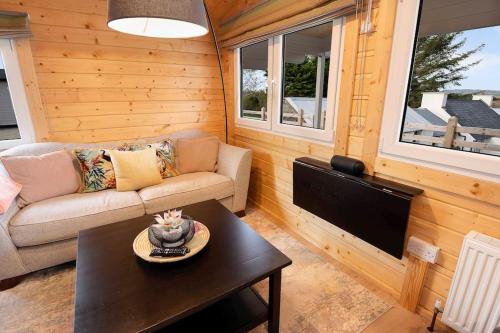 a living room with a couch and a table at Luxury Log Cabin with Private Hot Tub & Sea Views in Letterkenny