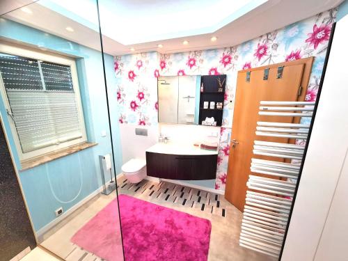 a bathroom with a pink rug and a sink at Ferienwohnung Am Helderbach 