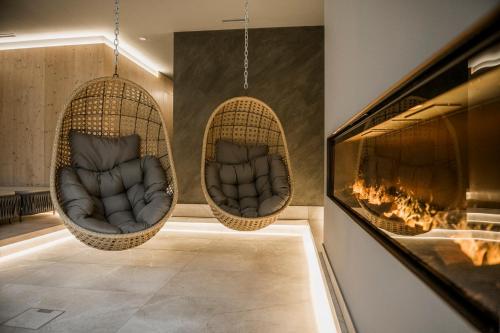 two hanging chairs in a room with a fireplace at AlpinSpa zur Post Apartment - Bergbahn im Sommer 2025 inklusive in Bad Gastein