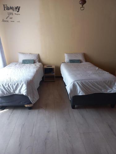 two beds in a room with wooden floors at Rocky Hills Guesthouse in Piet Retief
