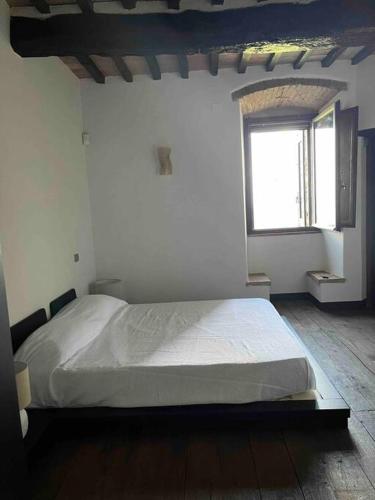 a bedroom with a white bed with a window at Medieval Tower in Umbria with Swimming Pool in Monte lʼAgello