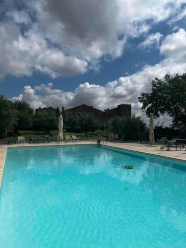 a large blue swimming pool under a cloudy sky at Medieval Tower in Umbria with Swimming Pool in Monte lʼAgello