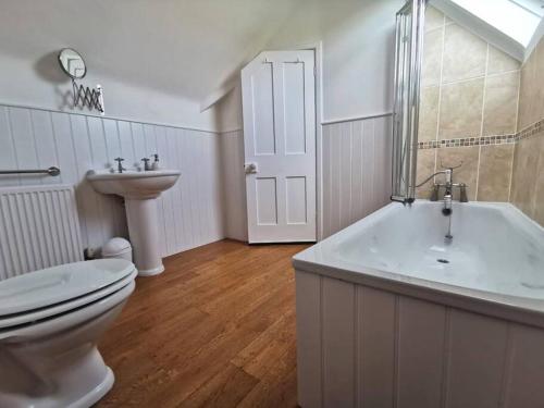 ein Badezimmer mit einem WC, einer Badewanne und einem Waschbecken in der Unterkunft Beautiful gate house a 4 minute walk from beach in Bersted