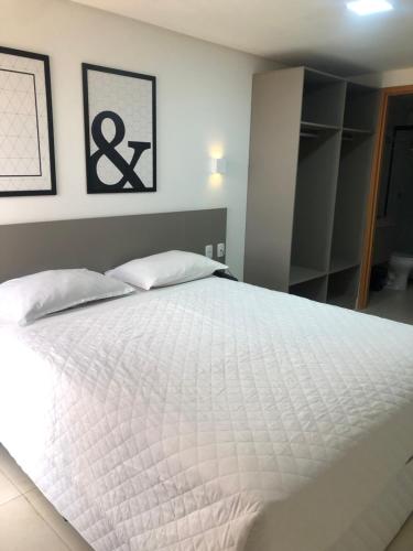 a bedroom with a large white bed with two pillows at Manaíra Apart Hotel in João Pessoa