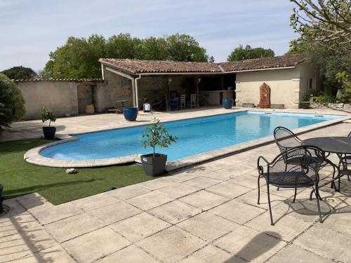 - une piscine dans une cour avec une table et des chaises dans l'établissement * Ancien domaine viticole de la Brandette *, à Gaillan-en-Médoc