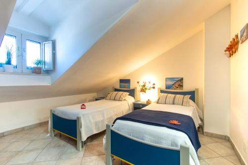 ヴァストにあるAppartamento Il Faro Plus - MyHo Casaのベッドルーム(ベッド2台付)が備わる屋根裏部屋です。