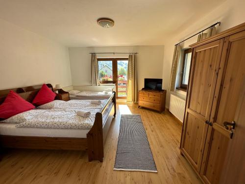 a bedroom with two beds with red pillows and a television at Holiday home Skalka in Mýto pod Ďumbierom